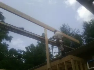 Carpenter setting a ridge beam over a new addition frame — Ice Dam Removal by Roofing Brothers in Blue Point