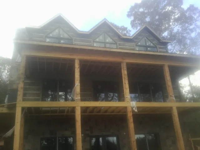 Dormers and porch framing on a large log home under construction — Roof Coating work by our crew in Blue Point