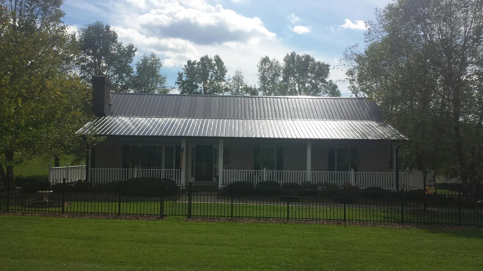 Gray metal roof on a brick ranch with a full width front porch — Gutter Guard Installation work by our crew in Blue Point