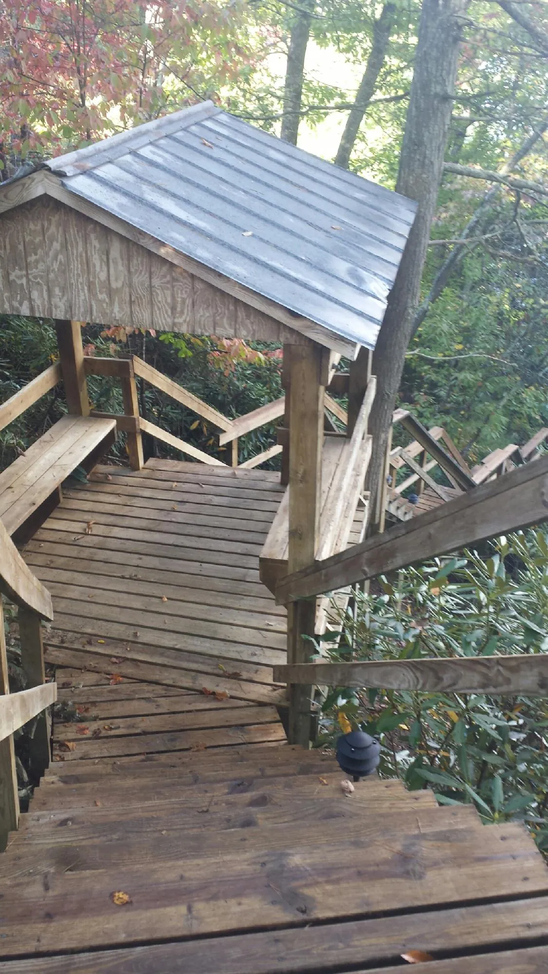Metal roofed shelter over wooden steps on a wooded walkway — Skylight Repair & Installation work by our crew in Blue Point
