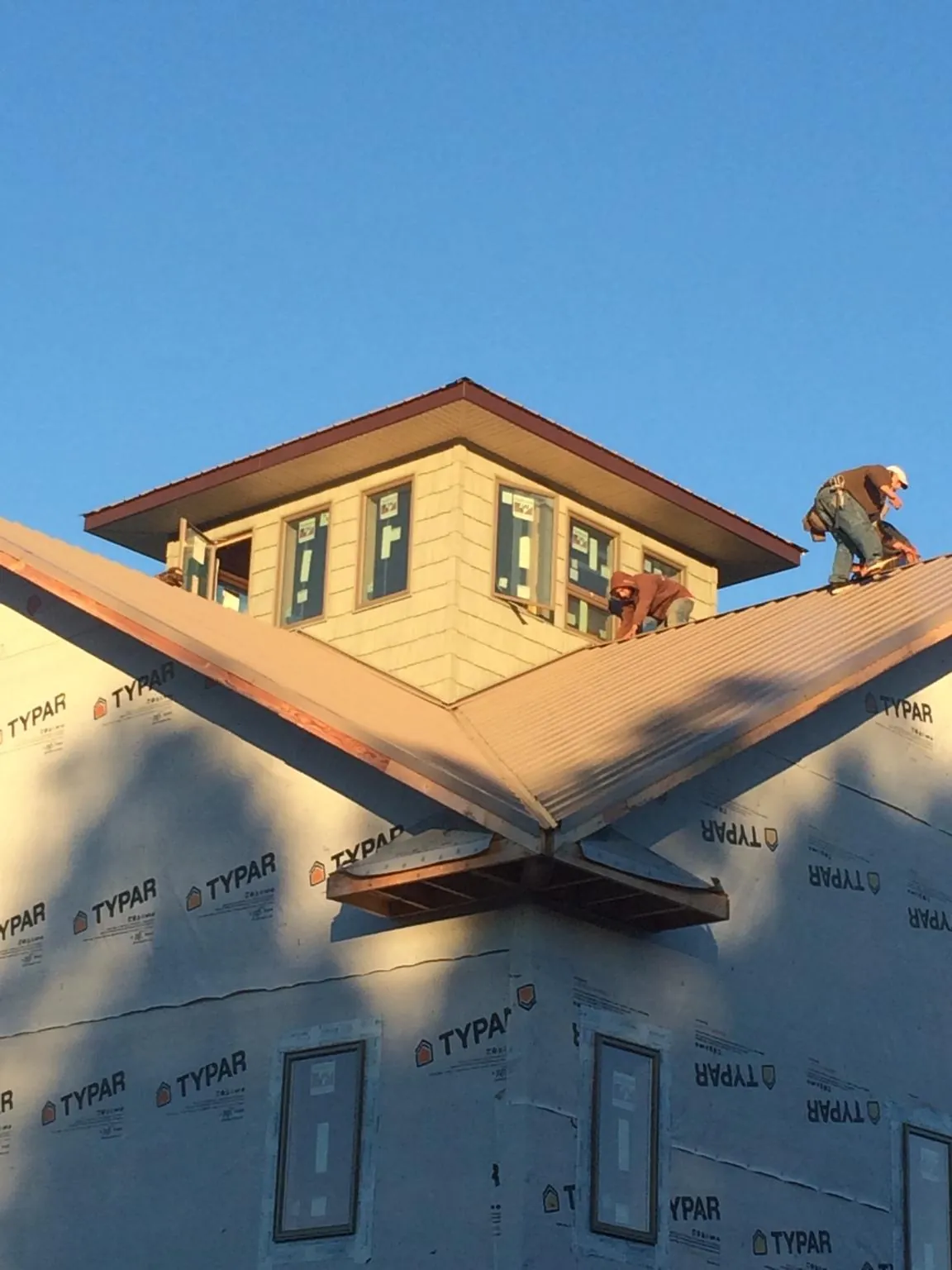 Roofers working around a rooftop cupola on a new metal roof at sunset — Roof Waterproofing in Blue Point by Roofing Brothers